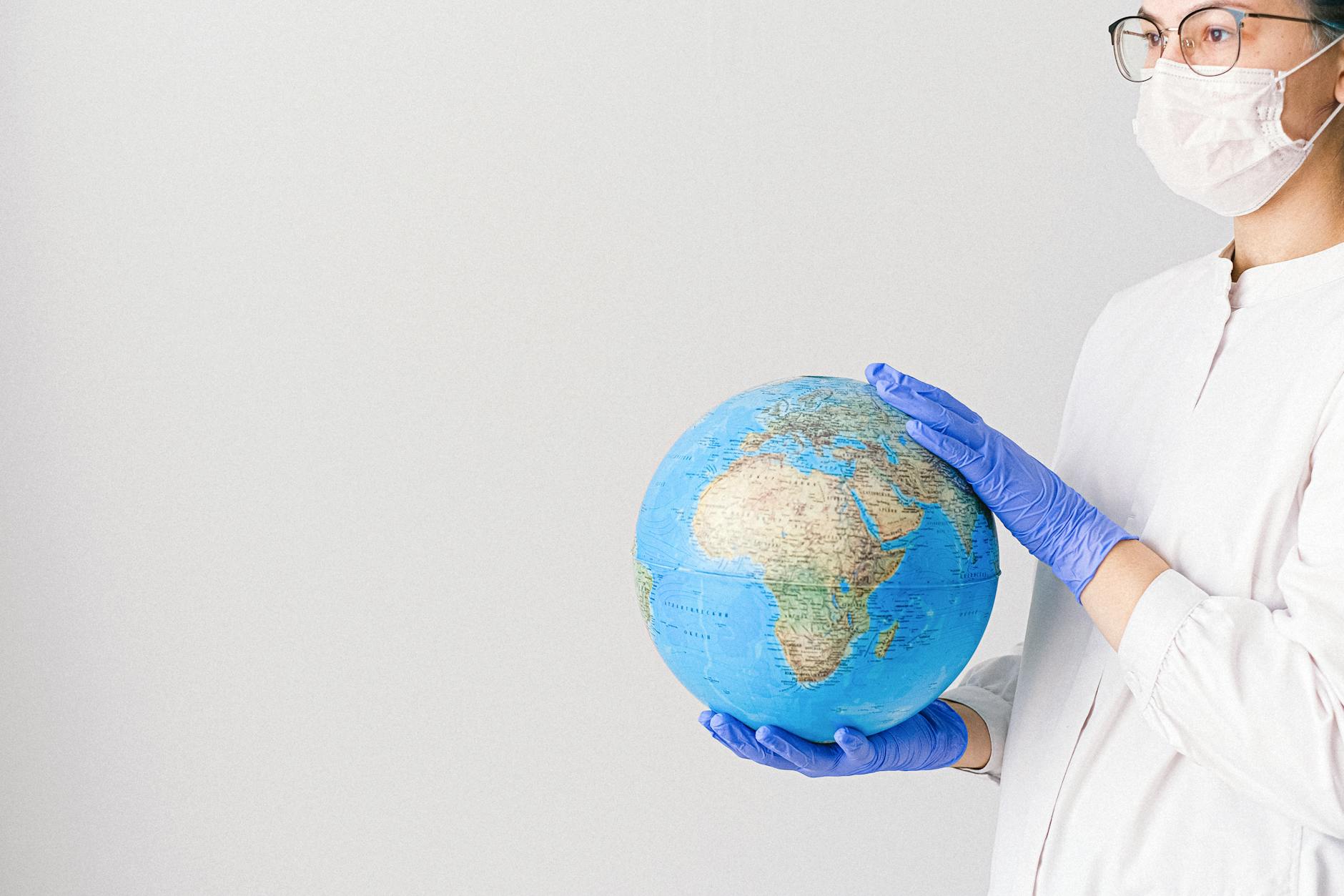 person with a face mask and latex gloves holding a globe