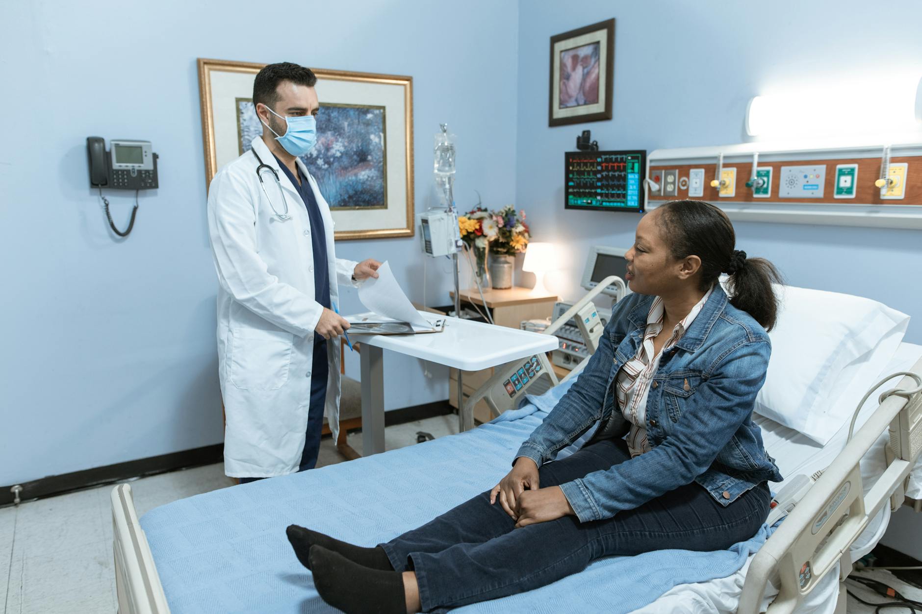 woman in blue denim jacket sitting on hospital bed